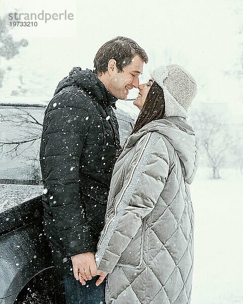 Seitenansicht smiley Paar küssen Schnee während der Fahrt