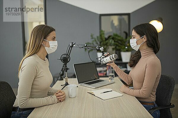 Seitenansicht Frauen mit medizinischen Masken  die gemeinsam Radio senden