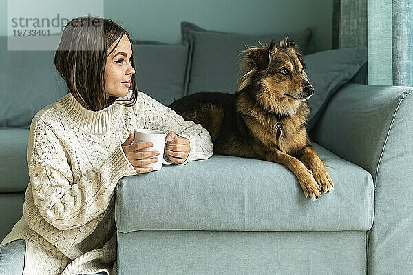 Frau trinkt Kaffee mit ihrem Hund zu Hause während der Pandemie