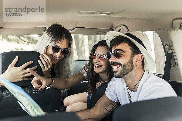 Trendy junge Freunde sitzen in modernen Auto suchen Karte