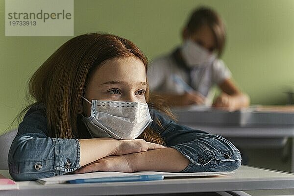 Kinder mit medizinischen Masken hören Lehrer Klasse