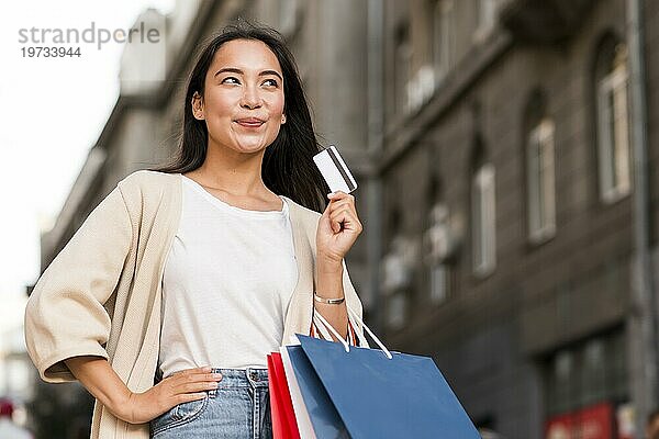 Glückliche Frau im Freien hält Einkaufstaschen Kreditkarte