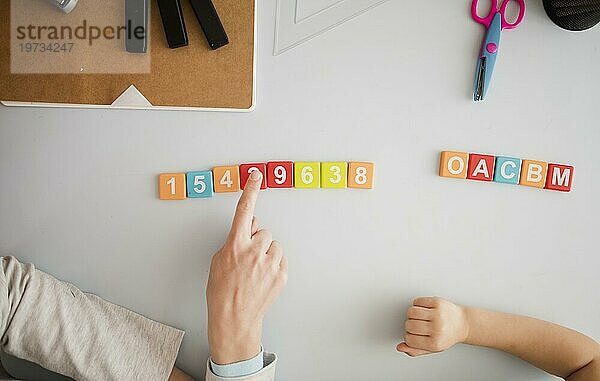 Draufsicht Tutor unterrichtet Kind Schreibtisch über Zahlen Buchstaben