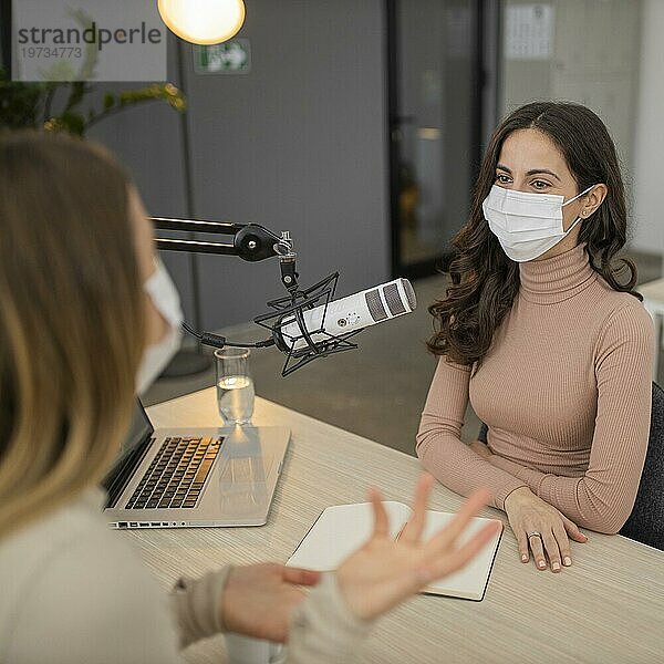 Zwei Frauen mit medizinischer Maske unterhalten sich über Funk