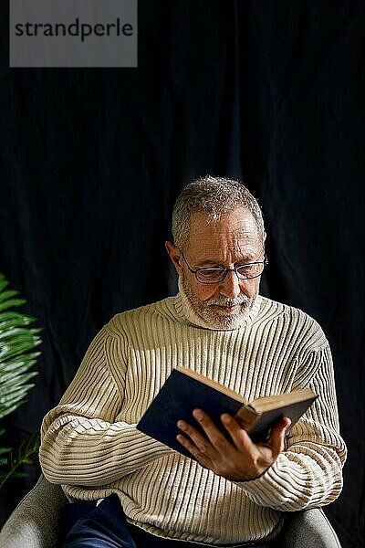 Älterer Mann mit Brille liest Buch