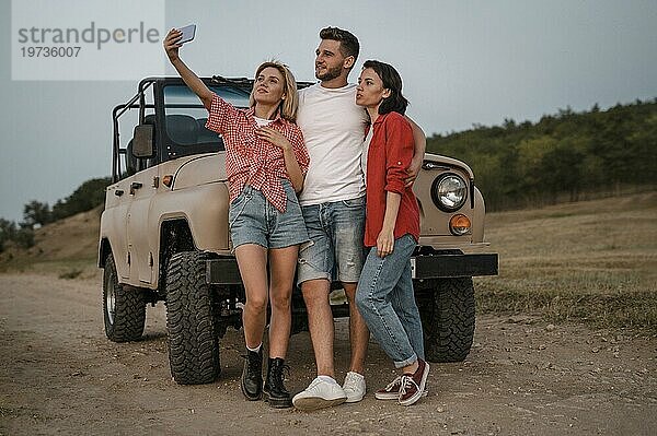 Drei Freunde machen ein Selfie mit ihrem Smartphone  während sie mit dem Auto unterwegs sind