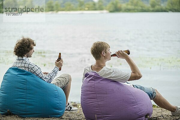 Erwachsene Männer entspannen sich mit Bier am Wasser