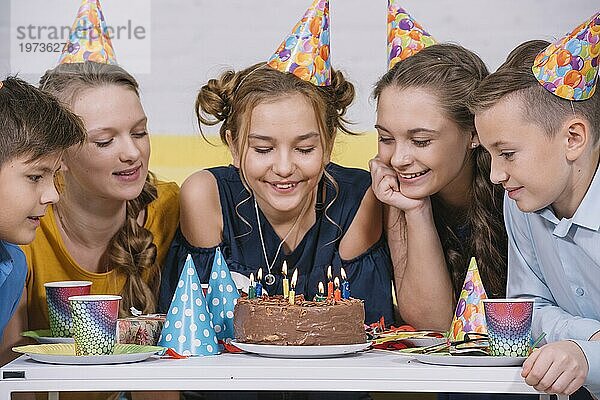 Gruppe Freunde suchen Geburtstagstorte mit Kerzen beleuchtet