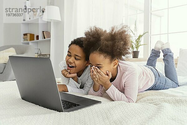 Zwei lächelnde Geschwister  die zusammen zu Hause Laptop spielen