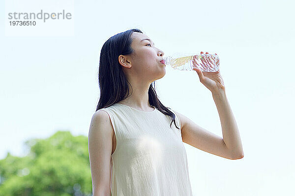 Junge Japanerin trinkt draußen Wasser