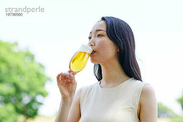 Junge Japanerin genießt draußen ein kühles Bier