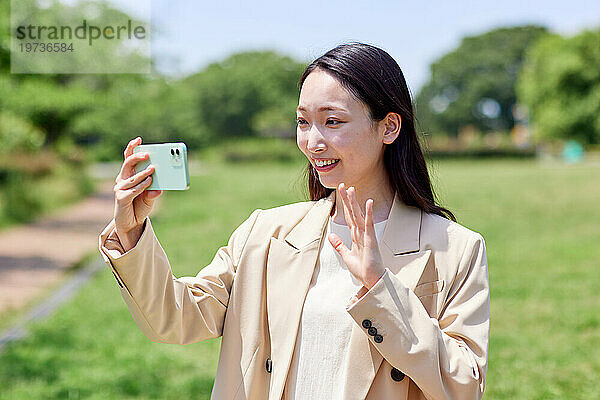 Junge Japanerin mit Smartphone draußen