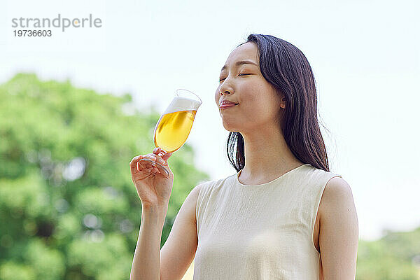 Junge Japanerin genießt draußen ein kühles Bier