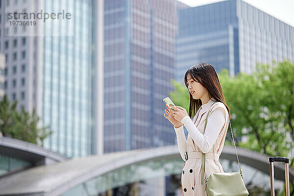 Junge Japanerin mit Smartphone draußen