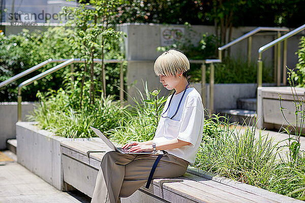 Junge Japanerin arbeitet an ihrem Laptop in der Innenstadt von Tokio