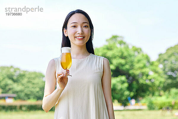 Junge Japanerin genießt draußen ein kühles Bier