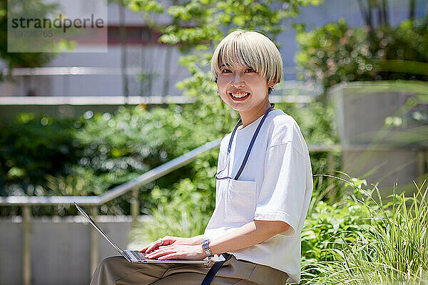 Junge Japanerin arbeitet an ihrem Laptop in der Innenstadt von Tokio