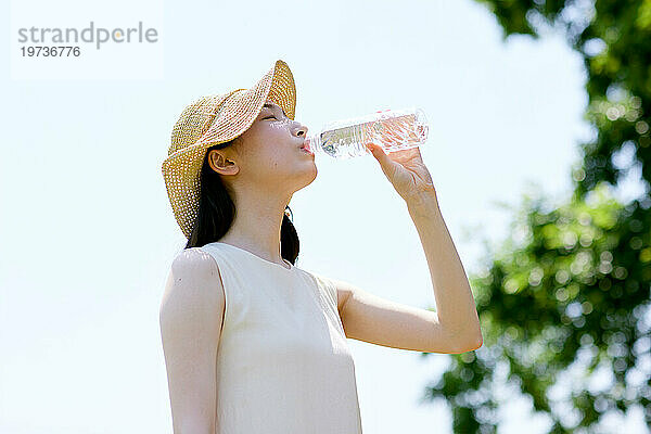 Junge Japanerin trinkt draußen Wasser