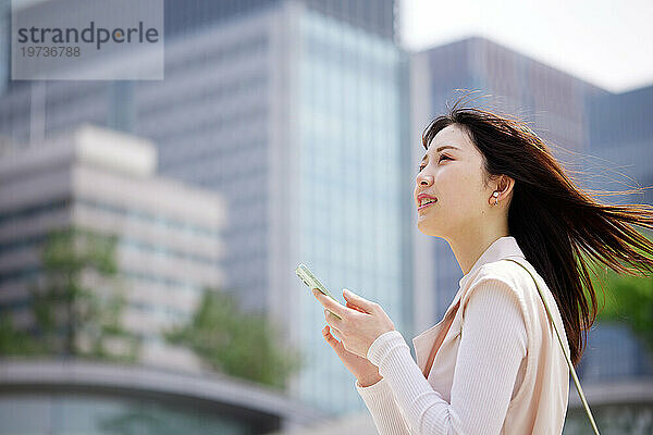 Junge Japanerin mit Smartphone draußen