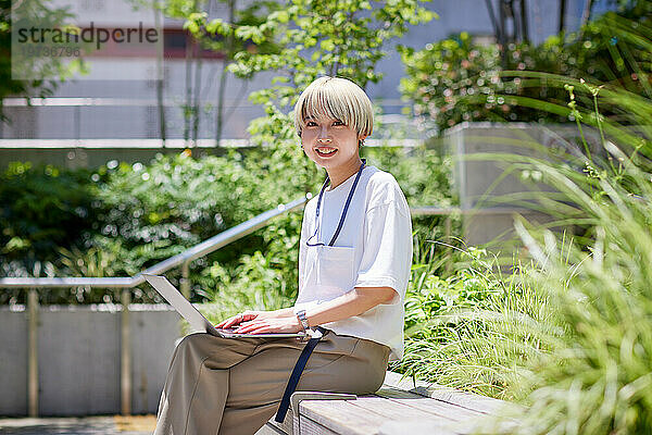 Junge Japanerin arbeitet an ihrem Laptop in der Innenstadt von Tokio