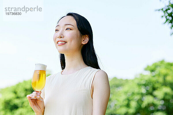 Junge Japanerin genießt draußen ein kühles Bier