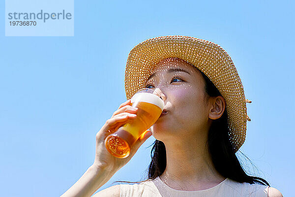 Junge Japanerin genießt draußen ein kühles Bier