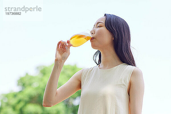 Junge Japanerin genießt draußen ein kühles Bier