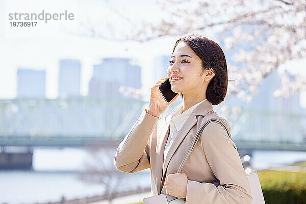 Junge Japanerin mit Smartphone draußen