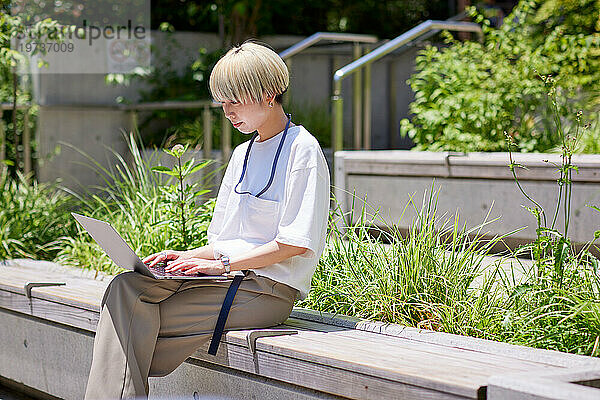 Junge Japanerin arbeitet an ihrem Laptop in der Innenstadt von Tokio