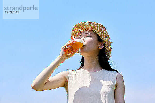 Junge Japanerin genießt draußen ein kühles Bier