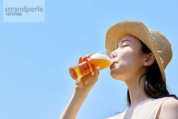 Junge Japanerin genießt draußen ein kühles Bier