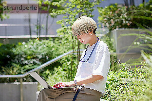 Junge Japanerin arbeitet an ihrem Laptop in der Innenstadt von Tokio