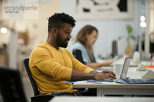 Afroamerikanischer Mann arbeitet mit Laptop im Büro