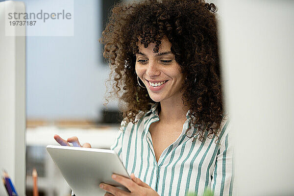 Young adult businesswoman using digital tablet while sitting at office
