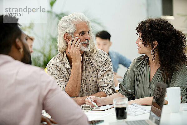 Erwachsener Geschäftsmann hört einer Kollegin während eines Meetings zu