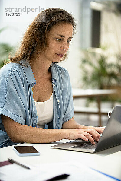 Erwachsene Frau benutzt Laptop  während sie im Designstudio am Laptop arbeitet