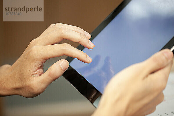 Nahaufnahme der Hände einer nicht erkennbaren Person mit einem digitalen Tablet