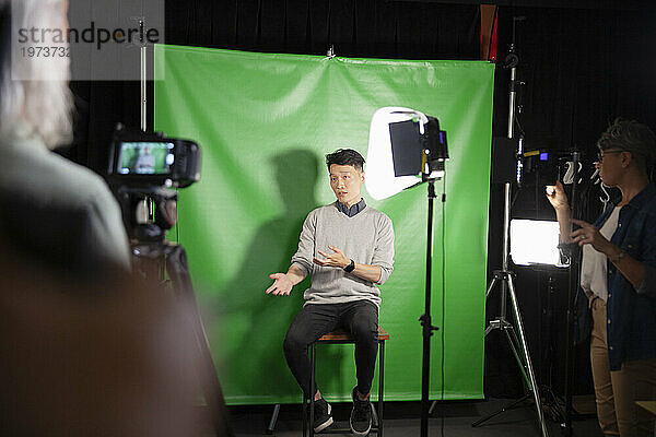 Junger erwachsener Mann gibt ein Interview  während er vor einem grünen Bildschirm sitzt
