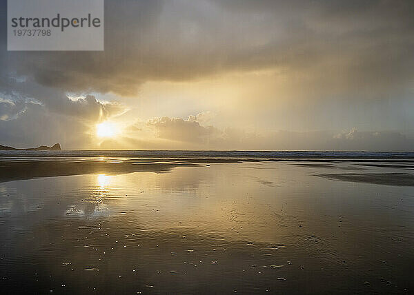 Regenwolken und Reflexionen am Strand von Rhossili bei Sonnenuntergang  der das Schiffswrack der Helvetia  Rhossili  Gower  Südwales  Vereinigtes Königreich  Europa zeigt