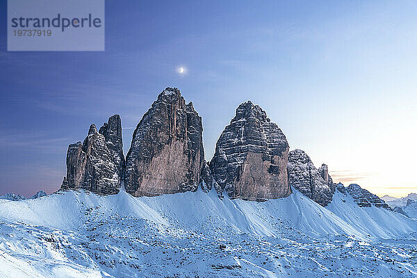 Mond über Tre Cime di Lavaredo in der Abenddämmerung  Winterzeit  Tre Cime di Lavaredo (Lavaredo-Gipfel) (Drei Zinnen)  Sesto (Sexten)  Dolomiten  Südtirol  Italien  Europa