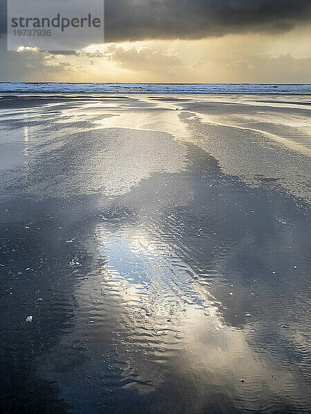 Regenwolken und Reflexionen am Strand von Rhossili bei Sonnenuntergang  der das Schiffswrack der Helvetia  Rhossili  Gower  Südwales  Vereinigtes Königreich  Europa zeigt