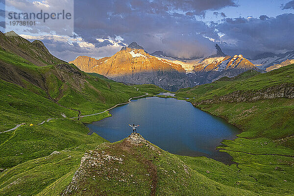 Fröhlicher Wanderer mit Blick auf den Bachalpsee und Bewunderung des Sonnenuntergangs über den Bergen des Berner Oberlandes  Grindelwald  Kanton Bern  Schweiz  Europa