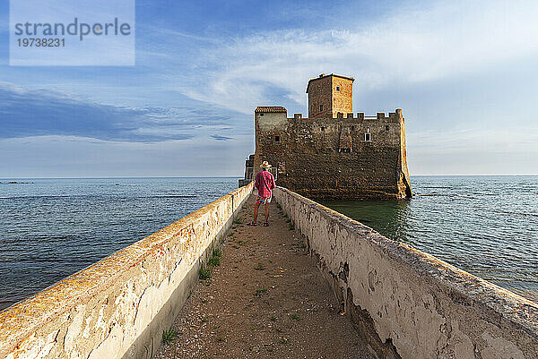 Tourist steht auf der Promenade und bewundert die Burg Torre Astura  Gemeinde Nettuno  Provinz Rom  Tyrrhenisches Meer  Latium (Latium)  Italien  Europa