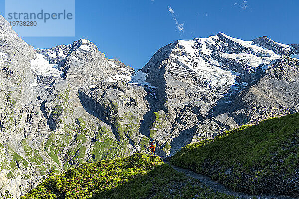 Wanderer wandert auf dem Sommerweg  umgeben vom Schweizer Gletscher  Oeschinensee  Kandersteg  Kanton Bern  Schweiz  Europa