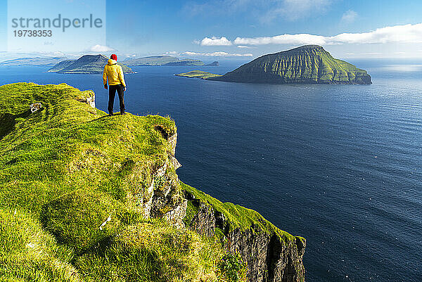 Wanderer steht auf einer Klippe und bewundert die schroffe Aussicht  Nordradalur  Insel Streymoy  Färöer-Inseln  Dänemark  Europa
