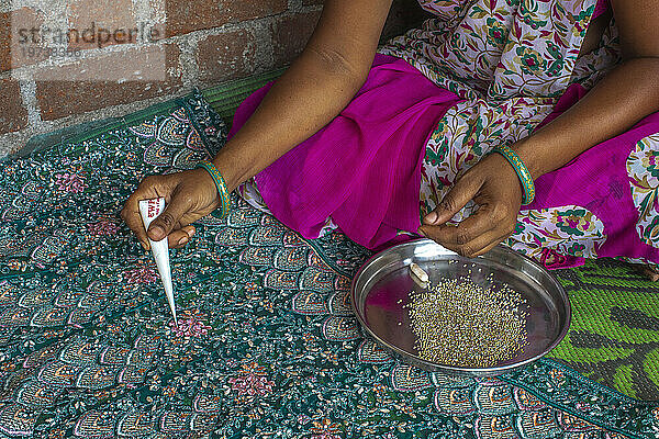 Adivasi woman sticking beads onto a sari in a village in Narmada district  Gujarat  India  Asia