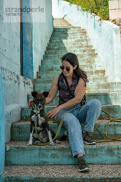 Frau mit Hund sitzt auf blauen Stufen  Juzcar  Region Pueblos Blancos  Andalusien  Spanien  Europa