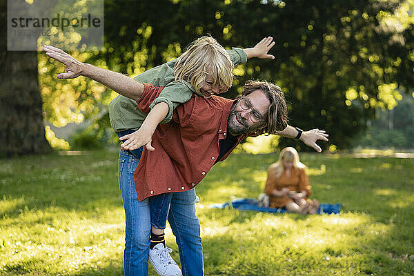 Lächelnder Vater  der Spaß hat und mit seinem Sohn im Park spielt