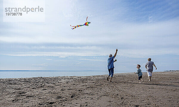 Großeltern lassen Drachen mit Enkel am Strand steigen