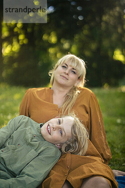 Lächelnde blonde Frau mit Junge entspannt sich im Park